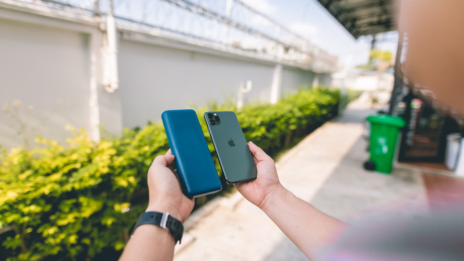 En hånd holder en smartphone forbundet til en powerbank